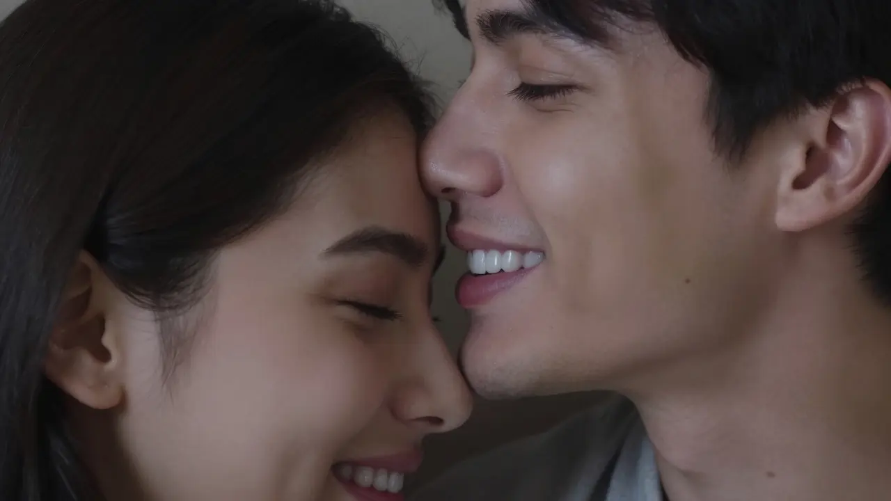 Muž políbí svou přítelkyni na čelo, jeho přirozený úsměv odhaluje keramické fasetky bez umělého vzhledu.